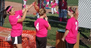 Head softball coach Sara Tani applies pink hairspray to junior Kristina Meska's hair in preparation for the team's