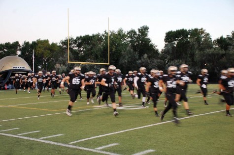 The Monarch football team runs out of the helmet at the beginning of their game against Mountain Range.