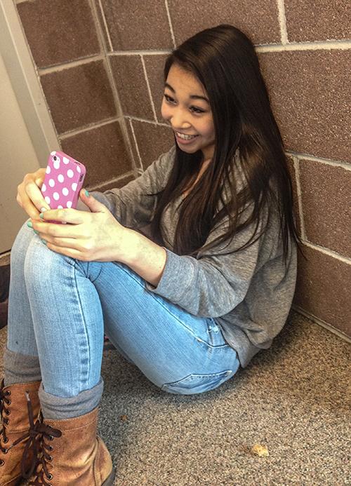 Freshman Mikaela Ichiyasu poses for a photo while sending a snapchat on her iPhone. Snapchatting has become more popular among younger generations, new users of the app surpass the amount that Facebook garners in news users, and may not be as safe or private as the company advertises.