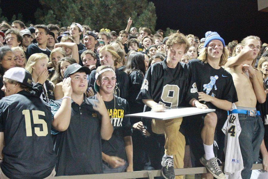 Senior Zach Litoff writes the next command for the student section while fellow students show their support in the crowd at the homecoming football game