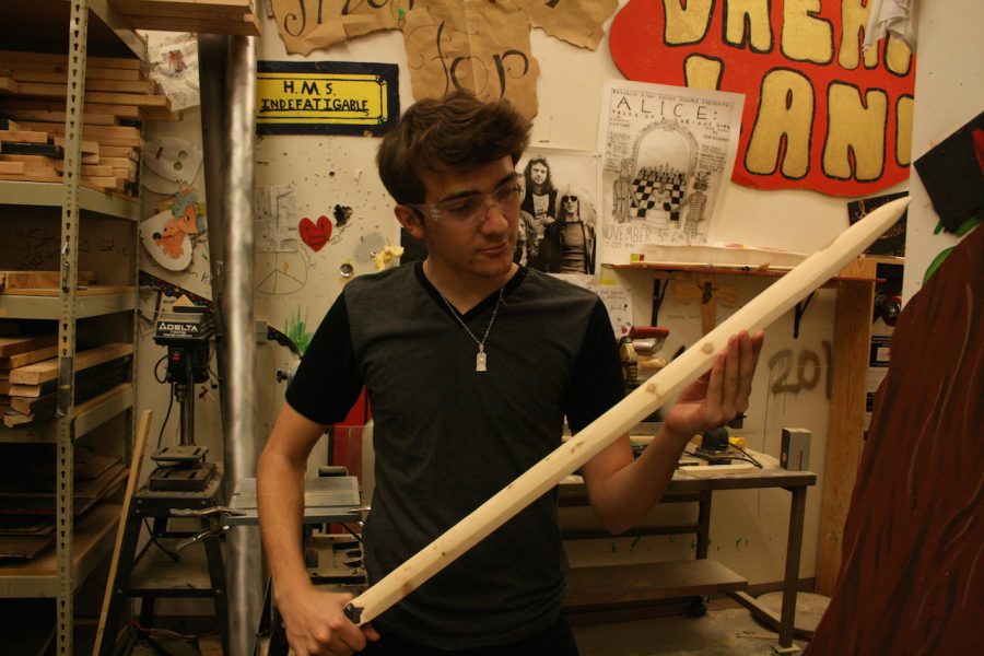 Senior Zion Mills inspects a sword that has been filed down and is ready to be painted. The sword is one of many props that was used for the cast of Macbeth.