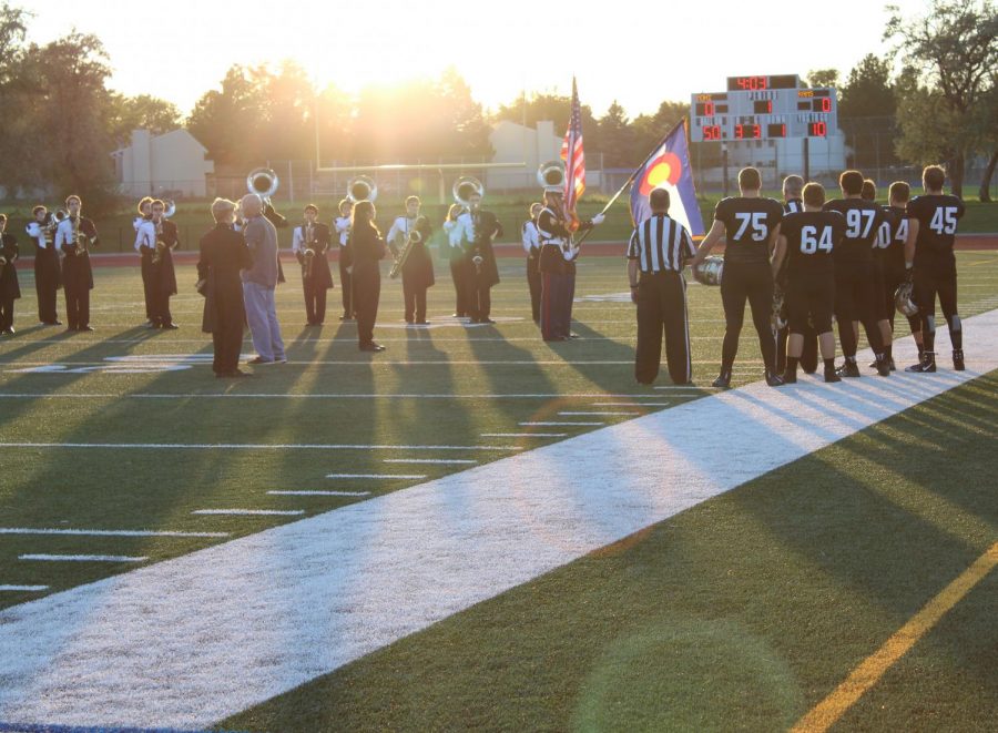 Football stands at attention while the marching band performs the National Anthem at the Aug 29 game against Longmont.