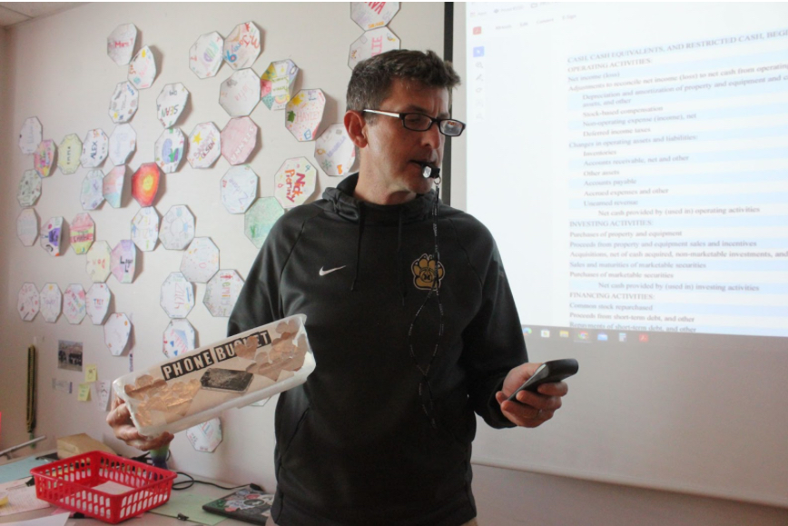 Business teacher Michael Blakey blows the whistle in his classroom while teaching. Blakey helped the girls’ team make a run at the state title in 2023.