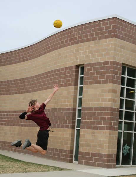Caden Coveney (11) practices serving volleyball against the wall outside of school.